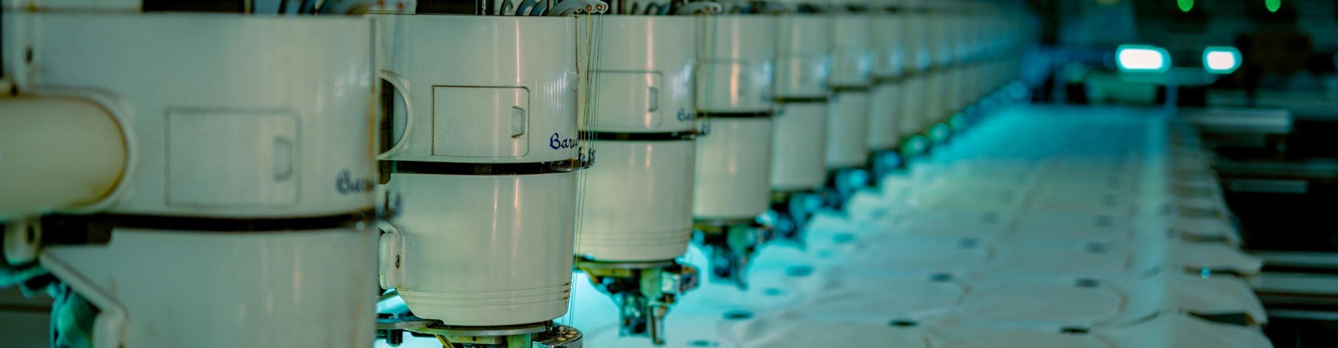 Row of industrial sewing machines in a textile factory producing garments.